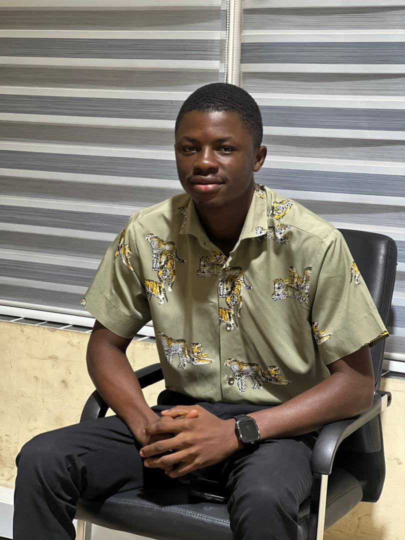 Laar Alfred Gontuaka, Project Manager at Chims Eagle Eye, in an olive patterned shirt against office blinds